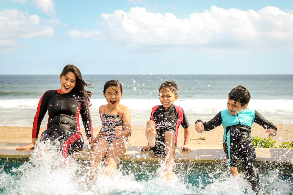 Family sitting on edge of pool on beach vacation